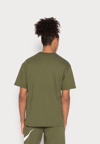 Olivgrön bomullströja med korta ärmar och rund halsringning. Har en avslappnad passform och inga synliga dekorationer.