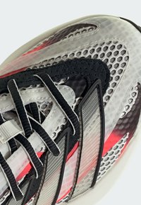 Mesh and synthetic sneaker in black, gray, and red. Features a rubber sole, lace closure, and textured overlays. Reflective accents present.