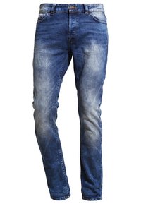 Jeans de mezclilla azul con acabado desgastado, diseño ajustado, estilo de cinco bolsillos y cierre de cremallera con un solo botón.