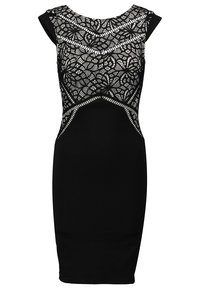 Svart klänning med en spetsöverdel med intrikata mönster, korta ärmar och en figurnära silhuett. Slätt tyg från midjan till fållen.