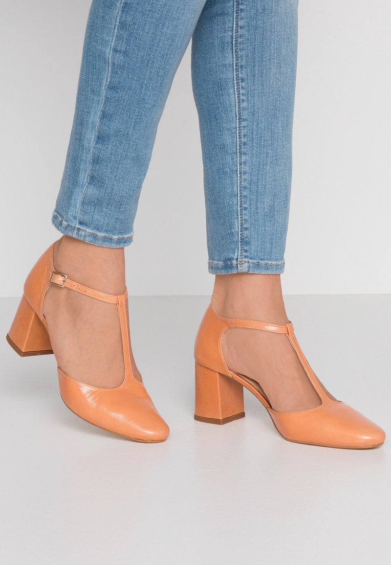 Chaussures à talon bloc en cuir pêche avec un design à bride en T. Caractéristiques : bout pointu et surface lisse avec une finition mate.