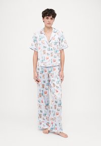 Pajama set s kratkim rukavima, izrađen od laganog materijala, s pastelnim uzorkom predmeta na bijeloj pozadini; hlače širokog kroja.