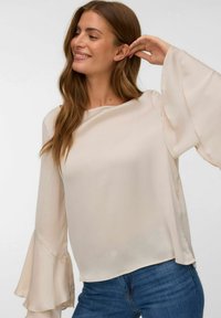 Blusa beige chiaro con maniche a campana fluide, realizzata in tessuto morbido. Il design presenta un collo a barchetta e una vestibilità rilassata.