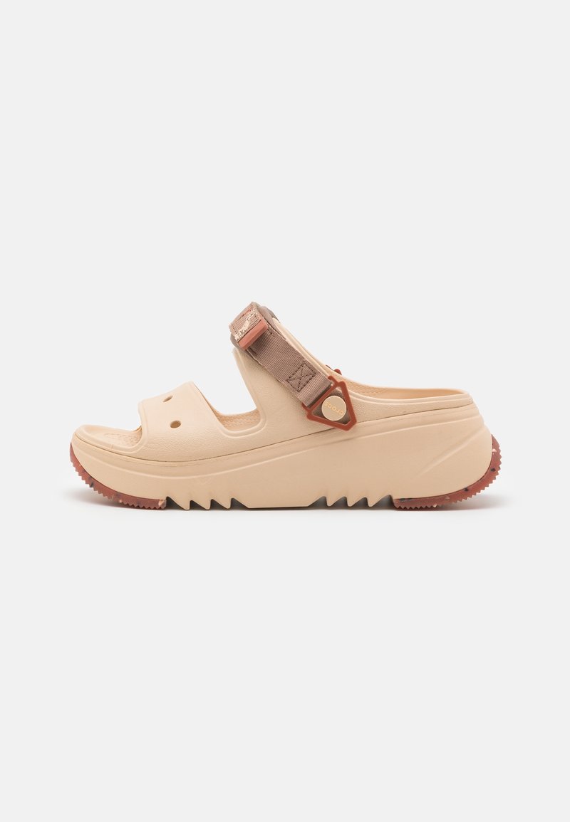 Beige platform sandal with adjustable brown strap, two front ventilation holes, textured sole, and zigzag tread pattern.
