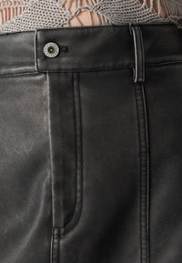 Black leather skirt featuring a front button closure, visible stitching, and a smooth texture. Details include a side seam and tailored fit.