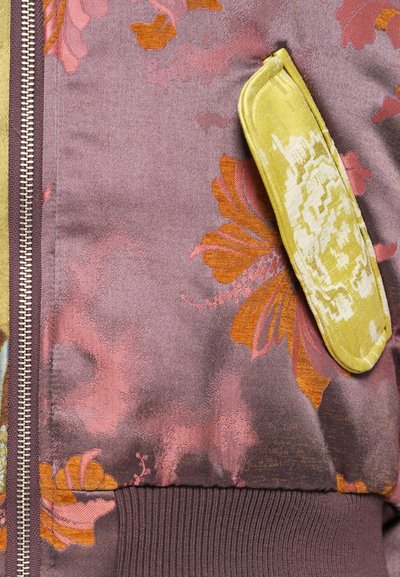 Satin bomber jaka ar ziedu rakstu purpura, apelsīnu un zaļās krāsās. Iespējas kontrastējoša tekstūrēta dzeltena kabata.