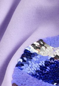 Hellviolette, gestrickte Stofffläche mit einem Bereich aus Pailletten in Blautönen, Silber und metallischen Akzenten, die ein strukturiertes Muster erzeugen.