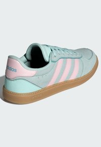 Světlé modré tenisky s růžovými pruhy, vyrobené z měkké semiše a syntetických materiálů, s béžovou gumovou podrážkou a raženým logem.