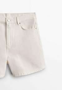 Short en jean blanc cassé avec bouton et fermeture éclair à l'avant, passants de ceinture et poches avant, présenté sur un fond blanc.