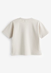 Beež puuvillane lühikeste varrukatega t-särk, ümara kaelusega ja külgedel lõhikuga ääres. Pehme, sile tekstuur, minimalistlik disain, nähtavad mustrid puuduvad.