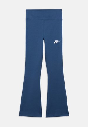 Niebieskie dzwony z wysokim stanem i białym logo Nike na górnej lewej części uda, prezentowane na białym tle.