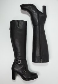 Mustat nahkaiset polvipituiset saappaat, joissa on teksturoidut pinnat, sivuvetoketju ja solkikoristeet nilkassa, tukevat korkot.