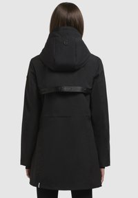 Black waterproof jacket with a hood, featuring a logo on the back and a horizontal strap. Smooth texture, mid-length design, long sleeves.