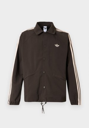 Pruun jakk kraega, ees klõpsud, kaks küljetaskut ja heledate roosade triipudega varrukatel. Rinnal on logo.