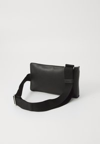 Black leather crossbody bag with a rectangular shape, textured surface, and an adjustable fabric strap featuring a metal buckle.