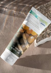 Tuben met lichaamssmeltmelk met een ontwerp featuring druiven, groen en bruin. Witte dop, 200 ml formaat, met productdetails op het etiket.