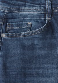 Jeans de mezclilla con un lavado azul oscuro, que cuentan con un bolsillo frontal, detalles deslavados y costuras en contraste alrededor de la cintura y los bolsillos.