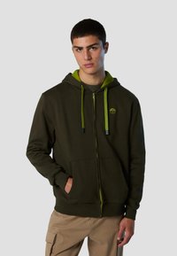 Felpa con cappuccio zip-up di colore verde scuro con cappuccio e lacci di un verde più chiaro. Presenta un logo sul lato sinistro del petto e tasche frontali.