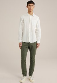 Vit långärmad skjorta med ficka, strukturerad tyg, i kombination med olivgröna slim fit-byxor och ljusa sneakers.