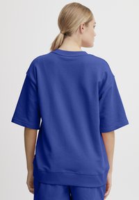 Overdimensioneret blå sweatshirt med korte ærmer, blød tekstur, ribbet halsudskæring og kant, der har et glat rygpaneldesign.