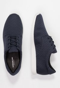 Marinblå texturerade sneakers med fiskbensmönster, rund tå och vit gummisula. Har snörning och vadderad innersula.