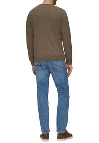 Brūns adīts džemperis ar apaļu kakla izgriezumu, ribotām piedurknēm, apvienots ar gaiši ziliem džinsu biksēm ar taisnu piegriezumu, redzamām šuvēm uz kabatām un brūnām kurpēm.