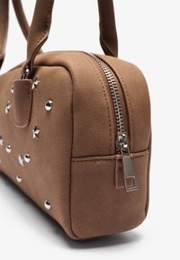 Sac à main en fausse suède marron avec fermeture éclair, embellissements en argent en forme d'étoile, texture lisse et poignées doubles pour le transport.