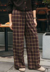 Pantaloni a gamba larga in tessuto a quadri bordeaux con motivo scozzese, dotati di vita elasticizzata e coulisse, realizzati in un tessuto morbido.