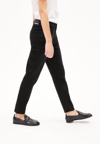 Svarta jeans med slim fit, utrustade med fem fickor, dragkedja och standard midja. Bärs med svarta slip-on-skor.