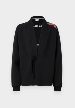 Sort jakke med snørresystem, afslappet pasform og ribbede manchetter, samt rød blomstermønsterbroderi på skulderen. Blødt stof.