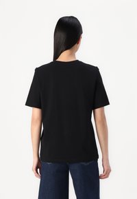 Zwart T-shirt met korte mouwen van katoen, met een ronde hals en een ontspannen pasvorm. De achterkant heeft geen ontwerpen of versieringen.