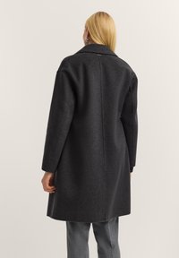 Dunkelgrauer Wollmantel mit breitem Kragen, mittellangem Schnitt und gerader Silhouette. Verfügt über lange Ärmel und eine Rückennaht.
