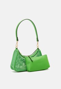 Malá zelená kabelka přes rameno s perforovanými bočnicemi a odnímatelným odpovídajícím zeleným zipovým pouzdrem na bílém pozadí.