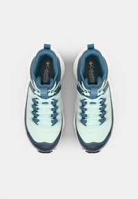 Des chaussures de randonnée bleu clair avec un dessus texturé, des accents bleu foncé, six boucles de lacet et une languette au talon pour un enfilage facile.