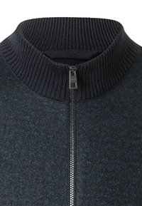 Mörk, strukturerad zip-up tröja med hög ribbad krage, med en slät dragkedja och ett blandat material för värme och komfort.