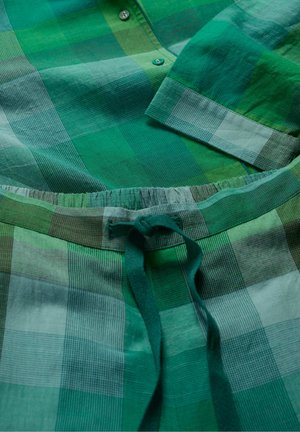Chemise à carreaux verts et pantalon assorti, présentant différentes nuances de vert avec des motifs à carreaux, un devant boutonnière et une taille élastique.