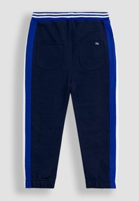 Pantaloni sport de copil de culoare bleumarin, cu dungi albastre și albe pe laterale, talie elastică cu dungi albastre și albe și două buzunare pe spate.