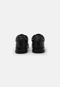 Black leather sneakers with a textured pattern and rubber soles. Features a branded heel and minimal accents in a sleek design.