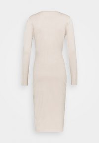 Abito bodycon a maniche lunghe color beige, realizzato in tessuto a coste. Presenta un collo rotondo e una silhouette aderente, che arriva appena sotto il ginocchio.