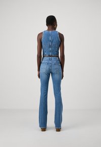 Denim crop top met een aansluitend ontwerp, blauwe kleur en een lichte textuur. Gecombineerd met hoge taille, flared blauwe jeans met achterzakken.