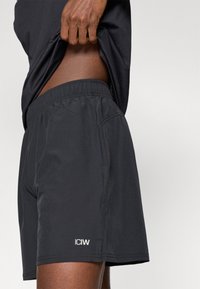 Melnas sporta šortus ar elastīgu jostasvietu, sānu kabatām un logo detaļu. Izgatavoti no viegla, gluda auduma.