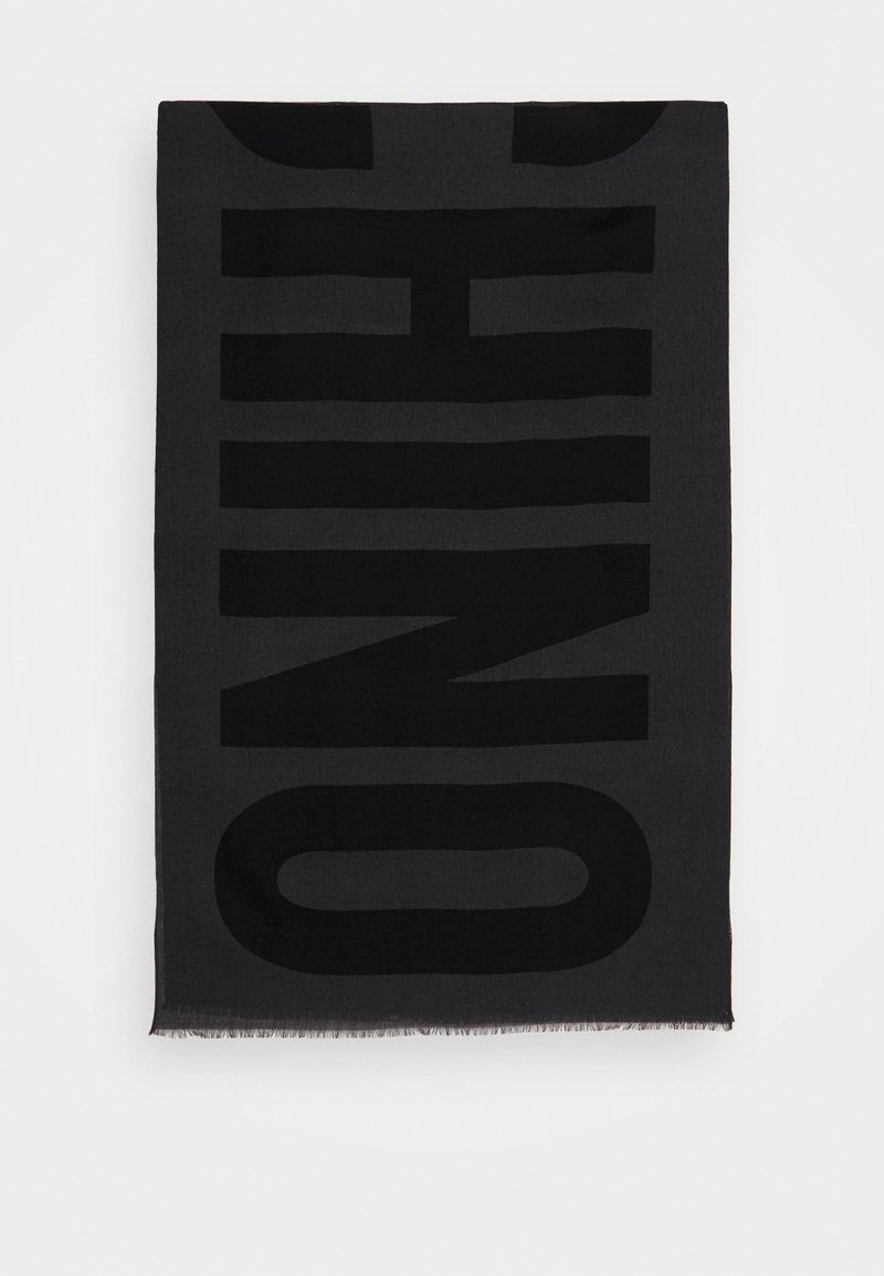 Écharpe rectangulaire noire avec le mot "HUGO" en grandes lettres épaisses et foncées, bordée de franges, sur un fond blanc.