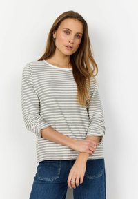 Grå og hvid stribet langærmet skjorte med rund halsudskæring og opfoldede manchetter, parret med blå denimjeans.