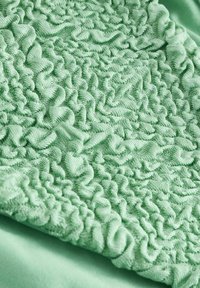 Gestructureerde mintgroene stof met verzamelde, gerimpelde patronen, die zacht, pluche materiaal en een gladde afwerking toont.