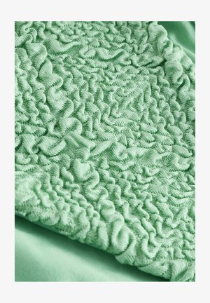 Textúrovaná mätovo-zelená tkanina s naskladanými, volánovými vzormi, zobrazujúca jemný, plyšový materiál a hladký povrch.