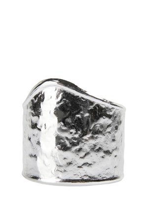 Anillo ancho de plata con textura martillada y un borde superior asimétrico y angulado sobre un fondo blanco.