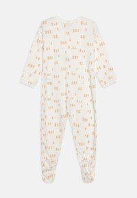 Hvid baby bodystocking lavet af blødt stof, med et let orange teddybjørnemønster over hele, lange ærmer og tætsiddende design med fødder.