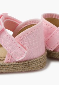 Sandalias de tela rosa con un acabado texturizado, que cuentan con un diseño de tiras cruzadas, suelas de yute trenzadas y cierre de velcro ajustable.