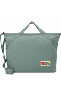 Groene stoffen tote bag met dubbele handvatten en een verstelbare schouderband. Heeft een Fjällräven logo patch. Glad van textuur en rechthoekige vorm.