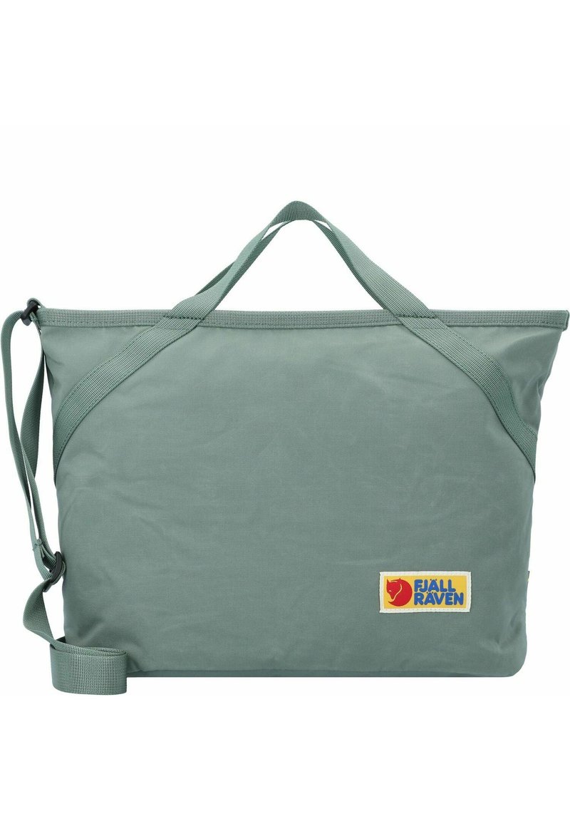 Groene stoffen tote bag met dubbele handvatten en een verstelbare schouderband. Heeft een Fjällräven logo patch. Glad van textuur en rechthoekige vorm.